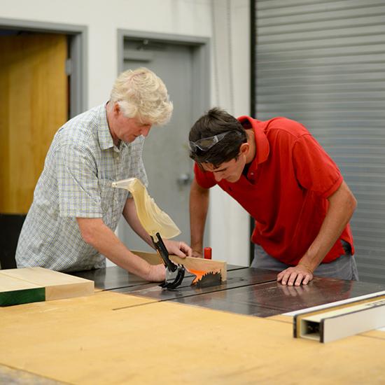 Art professor Phillip Shore sculpting wood with student